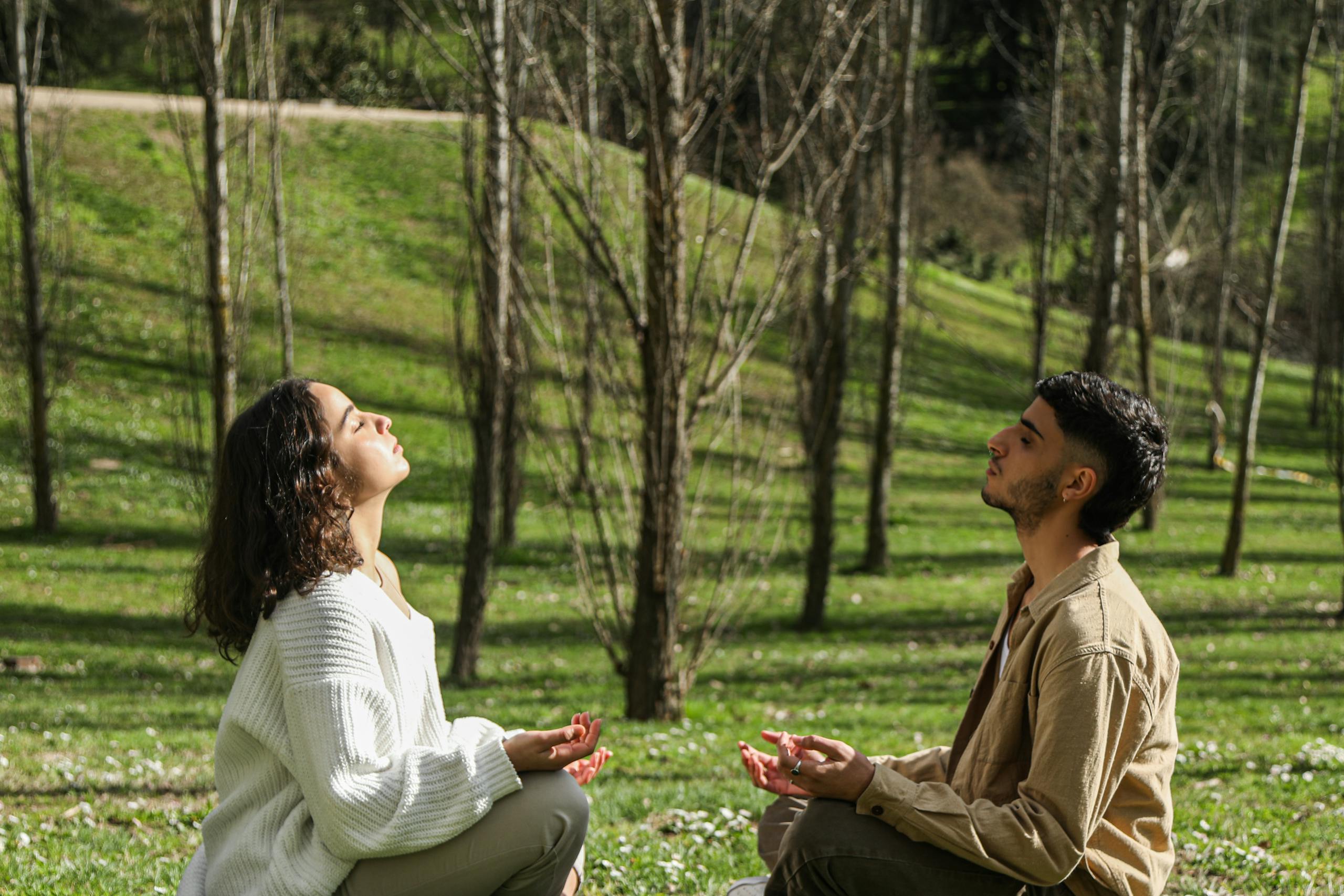 Two adults meditating in a serene park, enjoying peace and relaxation.